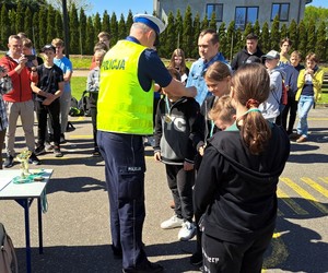 Policjant w żółtej kamizelce odblaskowej wręcza medal zawodnikowi.