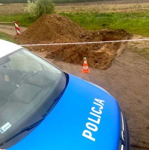 Radiowóz stojący przy otaśmowanym wykopie w którym znajduje się niewybuch z okresu II Wojny Światowej.