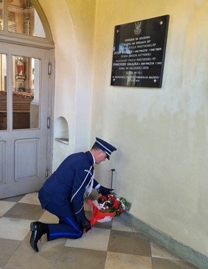 I Zastępca Komendanta w trakcie składania kwiatów przy tablicy upamiętniającej poległych policjantów.
