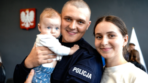 Policjant pozuje z rodziną do zdjęcia po zakończonym ślubowaniu.