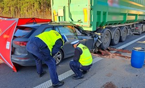 Policjanci w żółtych odblaskowych kamizelkach podczas oględzin uszkodzonych pojazdów. Funkcjonariusze sprawdzają stan opon w volkswagenie.