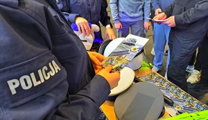 Policjanci na targach edukacyjnych EDU DAY stoją przy swoim punkcie informacyjnym i rozmawiają z maturzystami.