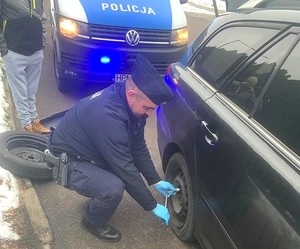 Policjant zmienia koło w aucie.