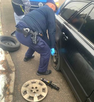 Policjant zmienia koło w aucie.