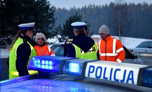 Członkowie komisji: policjanci, strażak oraz przedstawiciele Generalnej Dyrekcji Dróg Krajowych i Autostrad na miejscu wypadku drogowego. w czasie pracy. Na poboczu zaparkowane pojazdy służb uczestniczących w pracach komisji z włączonymi światłami błyskowymi.