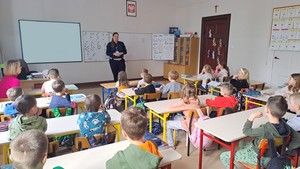 Policjantka prowadzi zajęcia w klasie. Uczniowie siedzą w ławce.