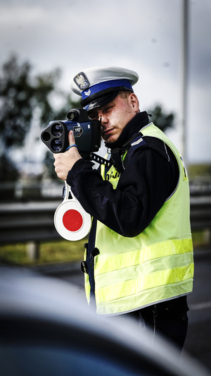 Policjant mierzy prędkość pojazdów.