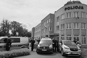 Policjanci stoją przy radiowozach i oddają hołd.