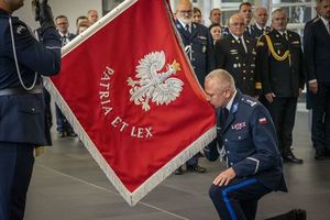 Komendant klęcząc wita się ze sztandarem.