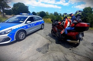 Policjant w czasie kontroli drogowej z udziałem motocyklisty.