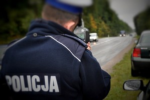 Policjant z drogówki mierzy prędkość pojazdów.