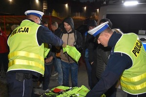 Policjanci wręczają elementy odblaskowe.