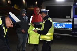 Policjanci wręczają elementy odblaskowe.