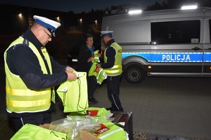 Policjanci wręczają elementy odblaskowe.