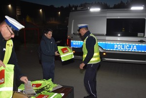 Policjanci wręczają elementy odblaskowe.