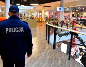 Policjant w okresie świątecznym stoi na holu w galerii handlowej.