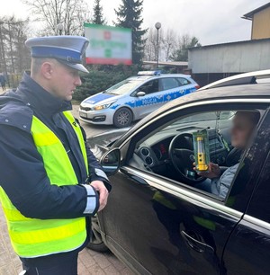 Policjant wręcza kierowcy latarkę.