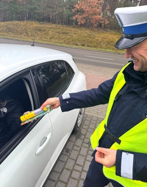 Policjant wręcza kierowcy latarkę.