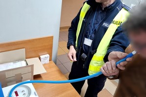 Policjant bada kierowcę alkomatem. Mężczyzna dmucha w niebieską rurkę.