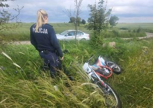 Policjantka stoi przy leżącym motocyklu.  W tle srebrne bmw.