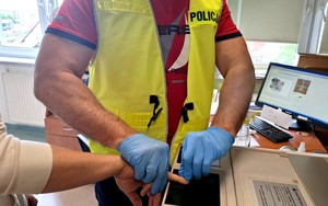 Policjant pobiera odciski palców od podejrzanego.
