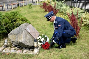 Komendant składa kwiaty przy tablicy upamiętniającej pomordowanych policjantów.