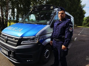 Policjant z Oddziałów Prewencji Policji w Gdańsku stoi przy radiowozie.