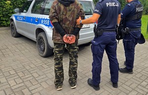 Policjanci z zatrzymanym mężczyzną. 39-latek ma założone kajdanki.