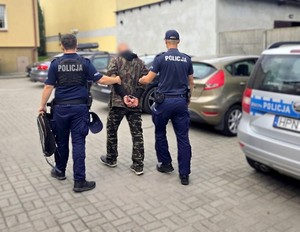 Policjanci z zatrzymanym mężczyzną. 39-latek ma założone kajdanki.