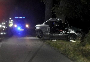 Rozbite na drzewie auto i pracujące w pobliżu niego służby.