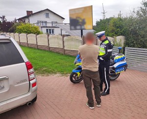 Policjant rozmawia z kierowcą zatrzymanym do kontroli drogowej.