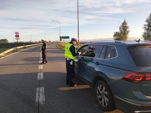 Policjant kontroluje alkomatem trzeźwość kierowcy siedzącego w aucie.