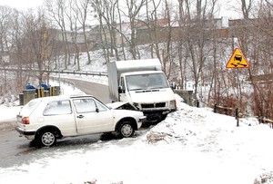 Dwa auta po zderzeniu. W pobliżu znak drogowy uwaga śliska jezdnia.