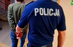 Policjant prowadzi zatrzymanego kierowcę.