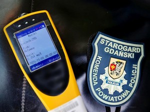 Alkomat wyświetlający na ekranie wynik badania oraz naramiennik z logiem Komendy Powiatowej policji w Starogardzie Gdańskim.