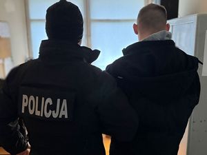 Policjant stoi z zatrzymanym mężczyzną.
