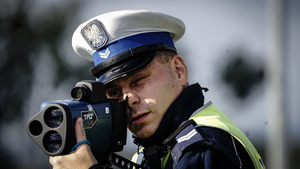 Policjant z drogówki mierzy prędkość pojazdów.