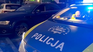 Radiowóz z włączonymi światłami błyskowymi i zaparkowane w pobliżu audi.