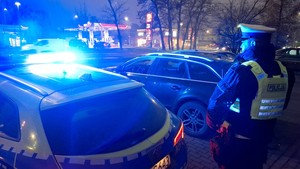 Radiowóz z włączonymi światłami błyskowymi i zaparkowane w pobliżu audi.