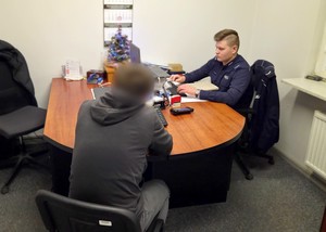 Policjant przesłuchuje zatrzymanego męzczyznę.