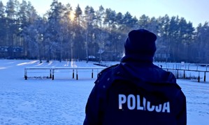 Policjantka z pomostu spogląda na zamarznięte jezioro.