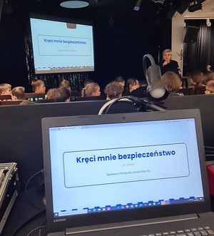 Policjantka prowadzi spotkanie z dziećmi w sali widowiskowej osiedlowego domu kultury.