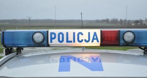 Kogut policyjnego radiowozu. Niebieski napis Policja na białym tle.