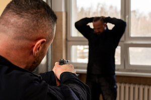 Policjant z bronią w ręku w trakcie zatrzymania pozoranta.