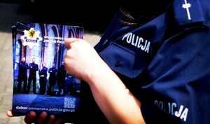 Policjantka trzyma ulotkę informacyjną dotyczącą doboru do służby w Policja.