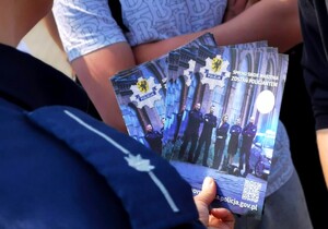 Policjantka trzyma ulotkę informacyjną dotyczącą doboru do służby w Policja.