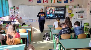 Policjantka w klasie szkolnej stoi i trzyma plakat dotyczący hejtu.