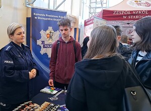 Policjantka rozmawia z młodzieżą w czasie Powiatowych Targów Edukacyjnych.