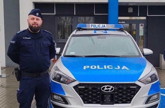 Policjant przy radiowozie.