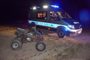 Zatrzymany Quad, a w tle radiowóz z włączonymi światłami błyskowymi.